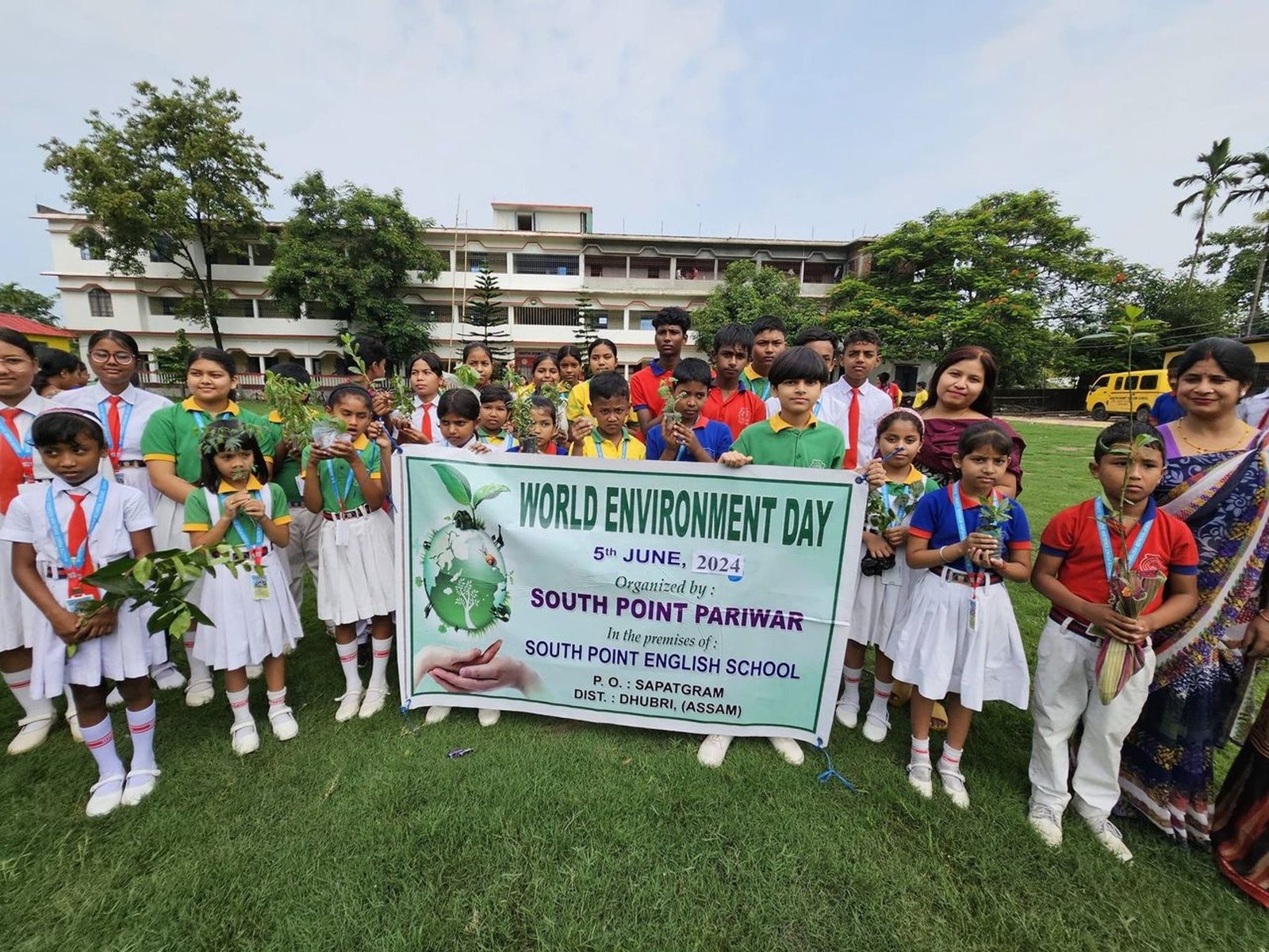 Students holding saplings behind the World Environment Day banner