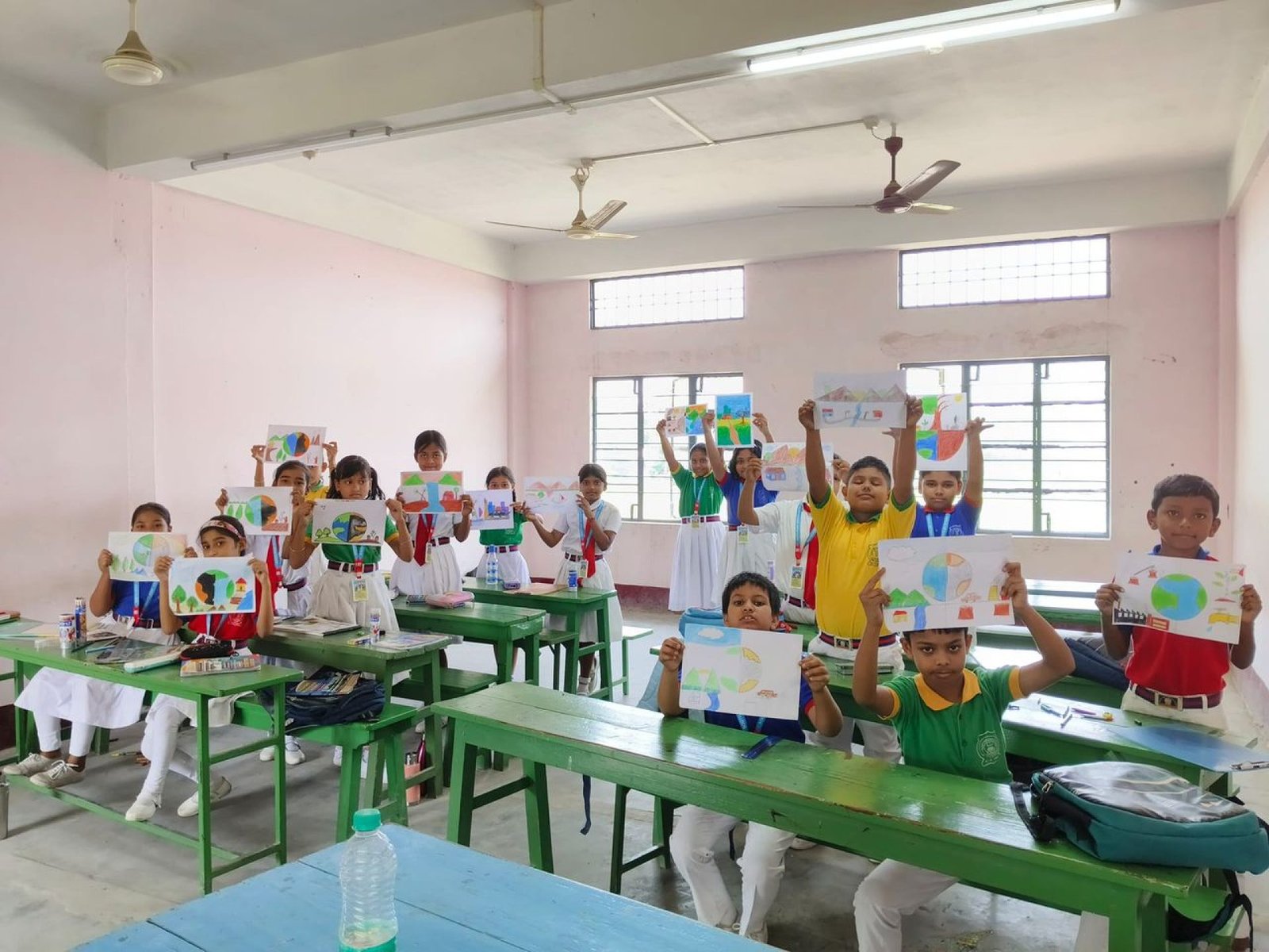 Primary students holding up the posters they painted in class